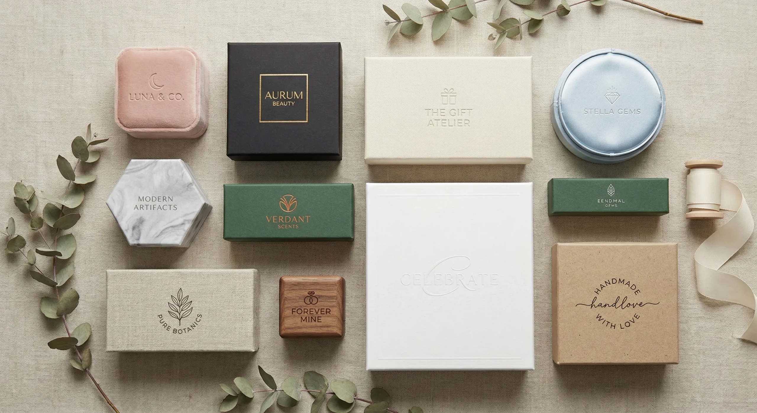 A flat-lay collection of various custom rigid boxes in different shapes, sizes, and materials including velvet, wood, marble, and matte finishes with gold-stamped logos.